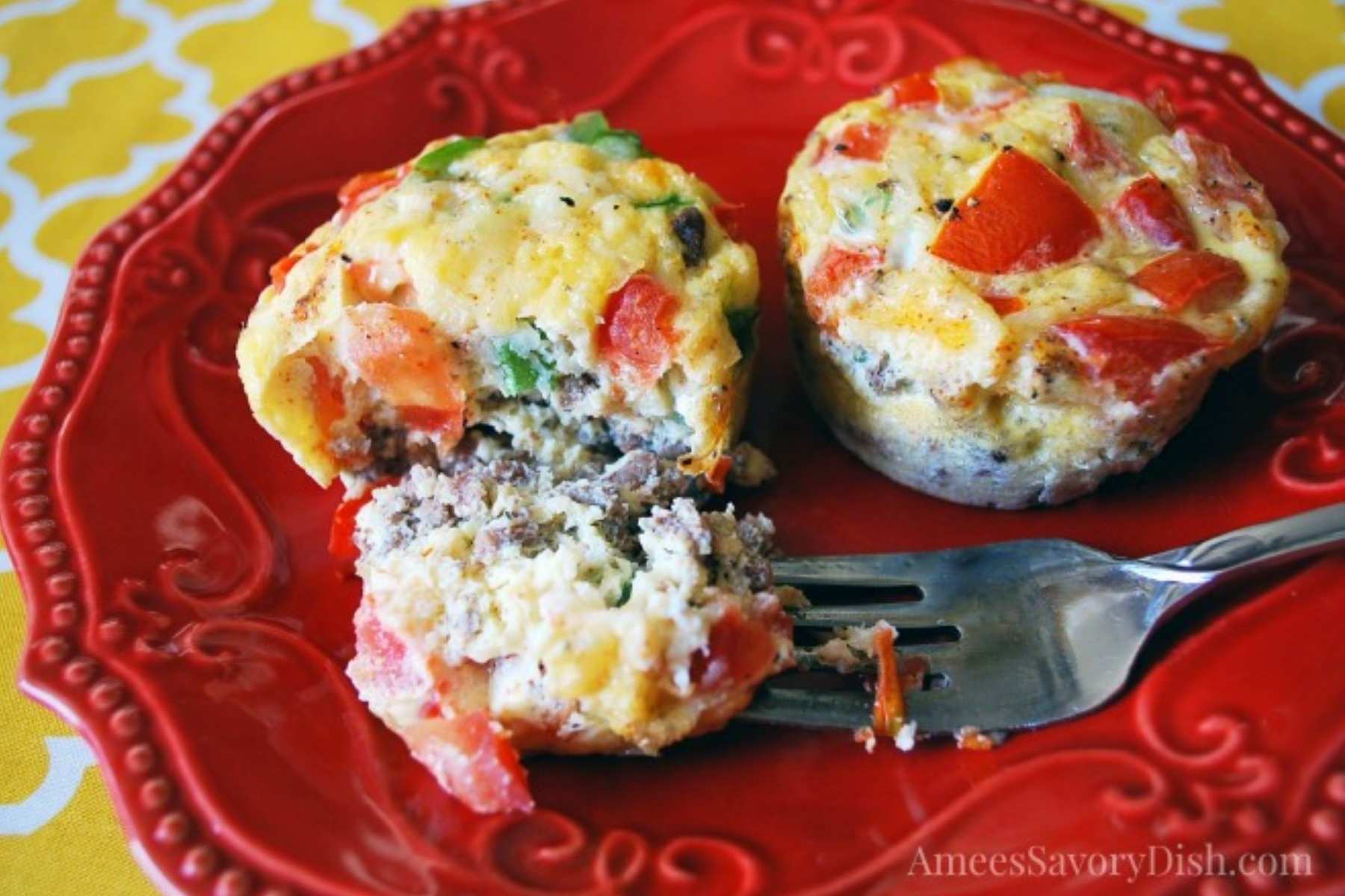 two egg muffins on a plate with one sliced with a fork 