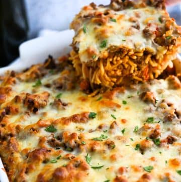 a spatula holding a serving of baked spaghetti over a pan of casserole