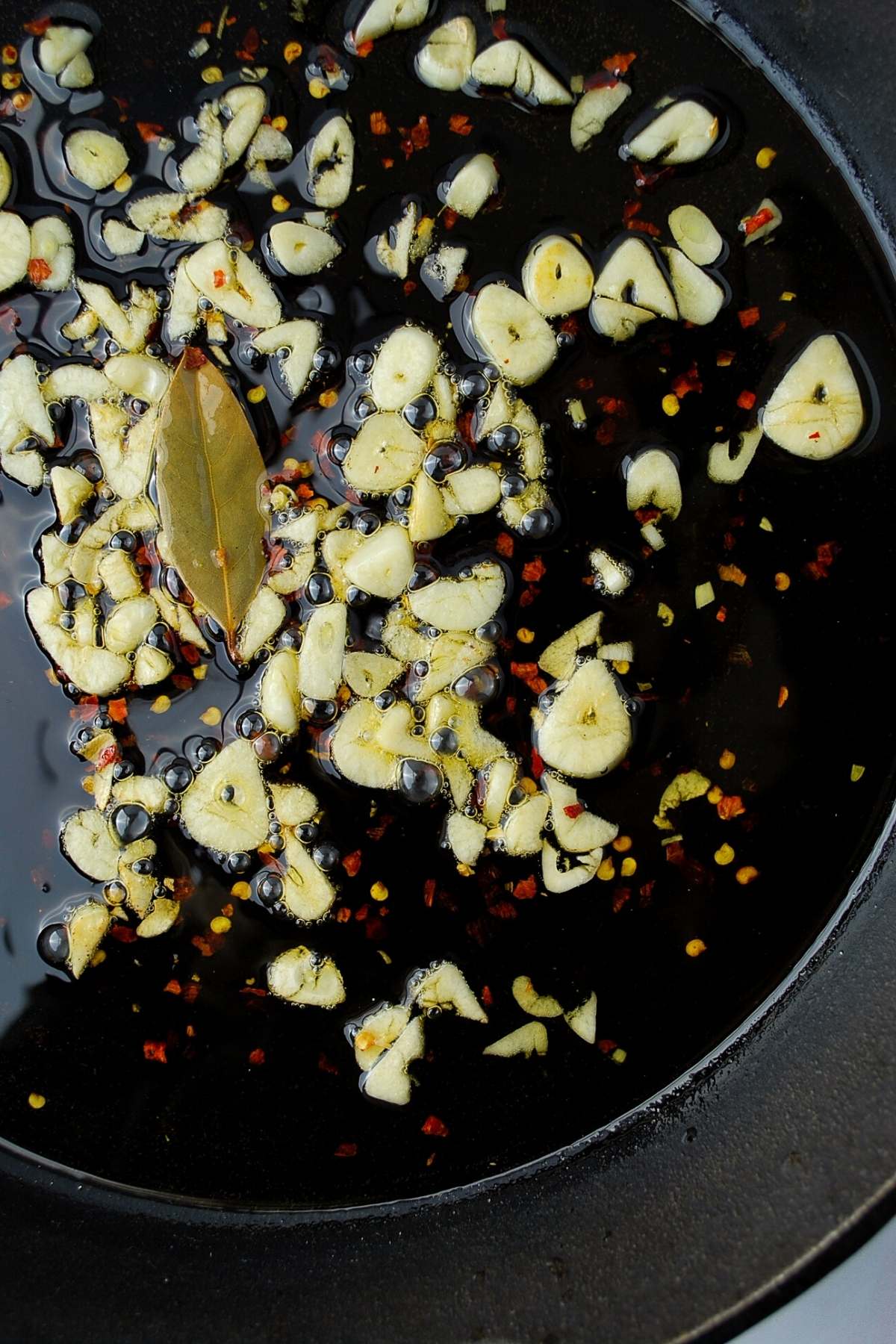garlic, pepper, and bay leaf cooking in olive oil