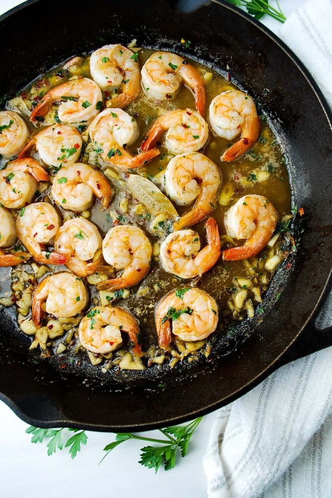 cooked prawns in garlic, olive oil, and spices in a cast iron skillet