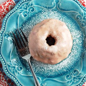 strawberry glazed donut on a blue plate dusted with powdered sugar