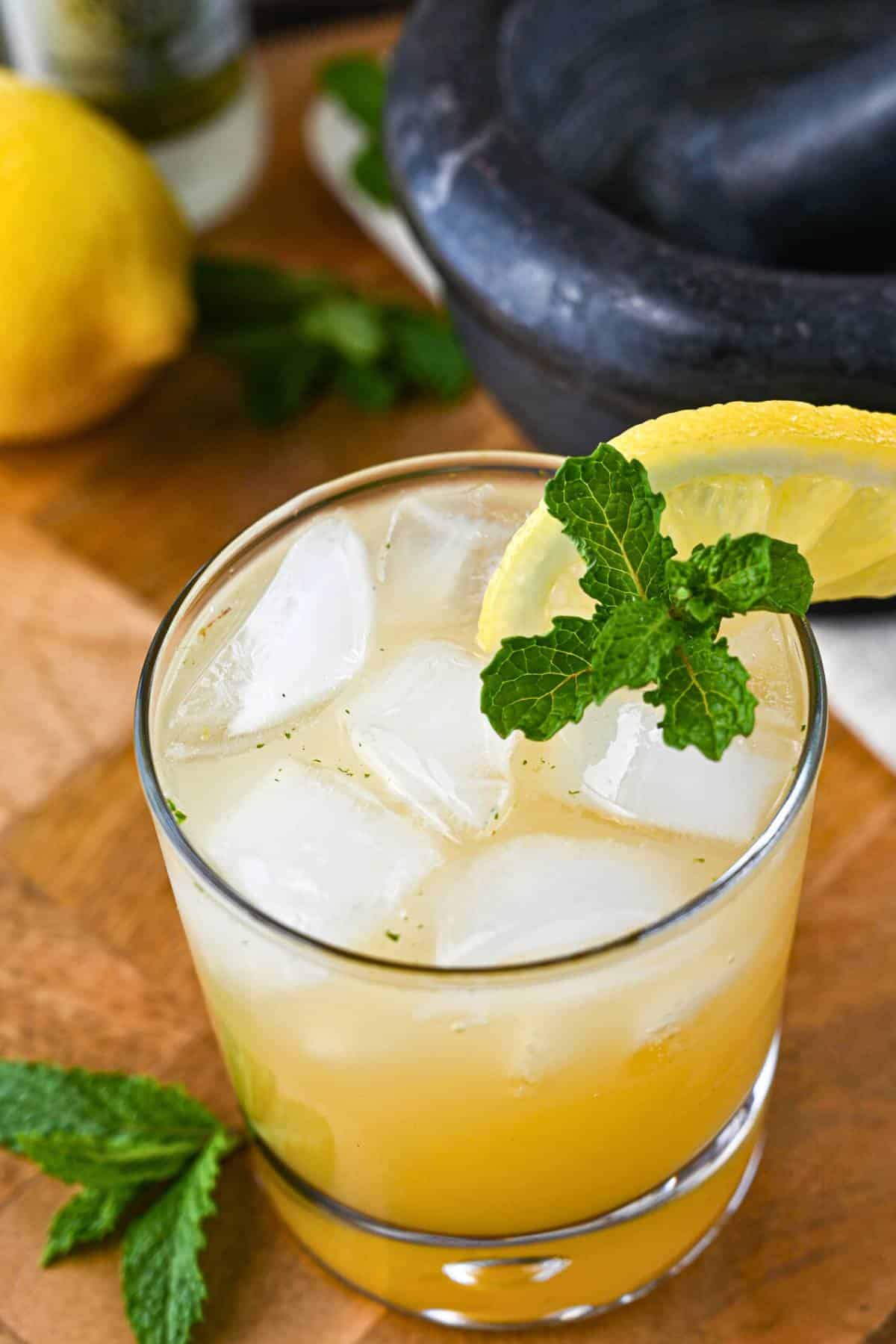 overhead photo of an apple ginger mocktail with mint and lemon with mint, lemon, and mortar and pestle in the background