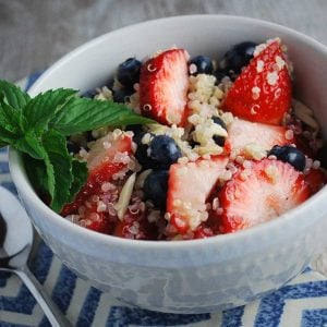 berries with cooked quinoa and almonds in a bowl with a sprig of mint