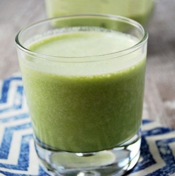 green shake in a glass with a blender container in the background