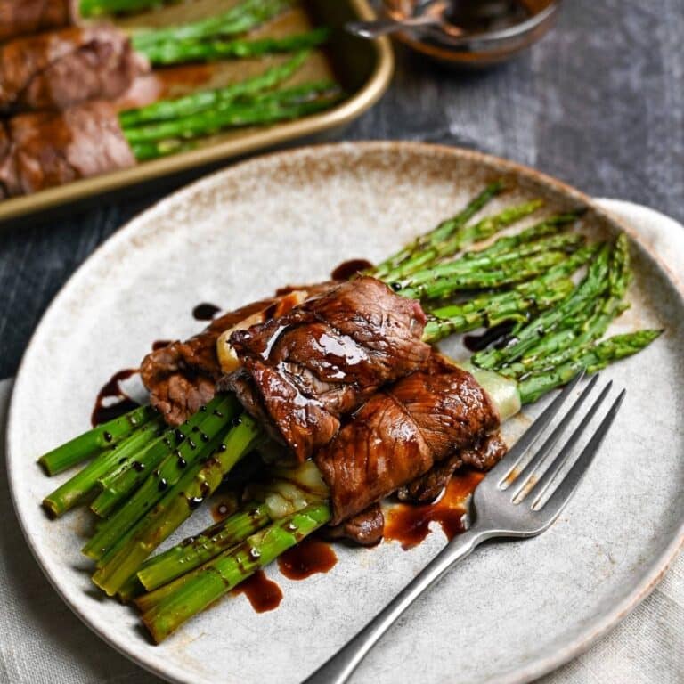 close up of steak asparagus rolls on a plate with a fork