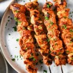 harissa marinated chicken skewers on a plate sprinkled with parsley