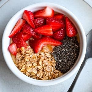 protein yogurt bowl with granola, chia seeds and fresh strawberries on top