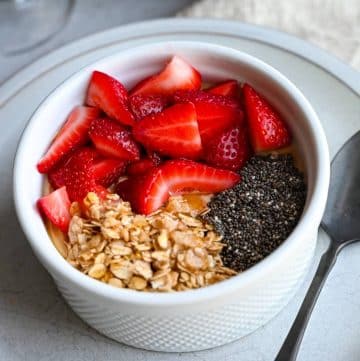 side view close up of a protein yogurt bowl with sliced strawberries, chia seeds, and low-fat granola