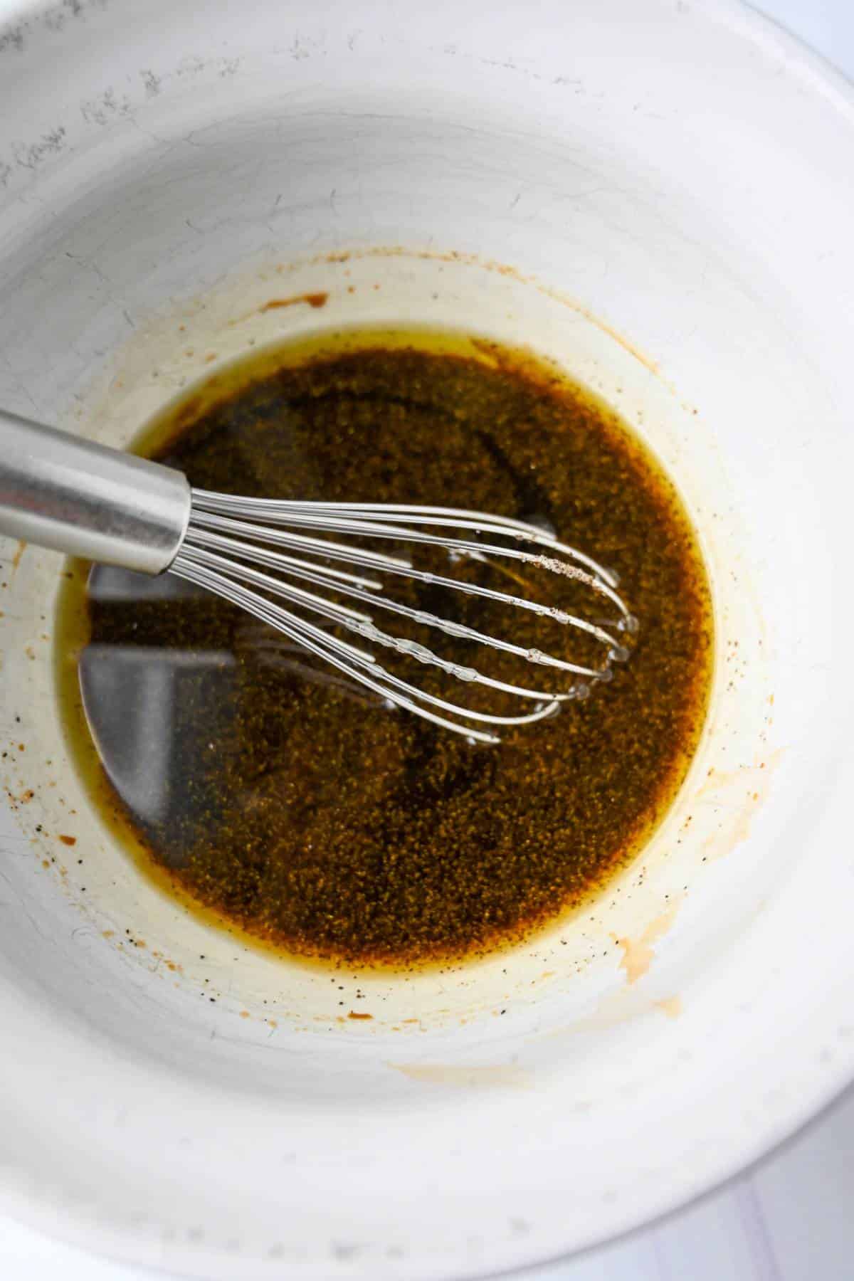balsamic dressing with a whisk in a white bowl