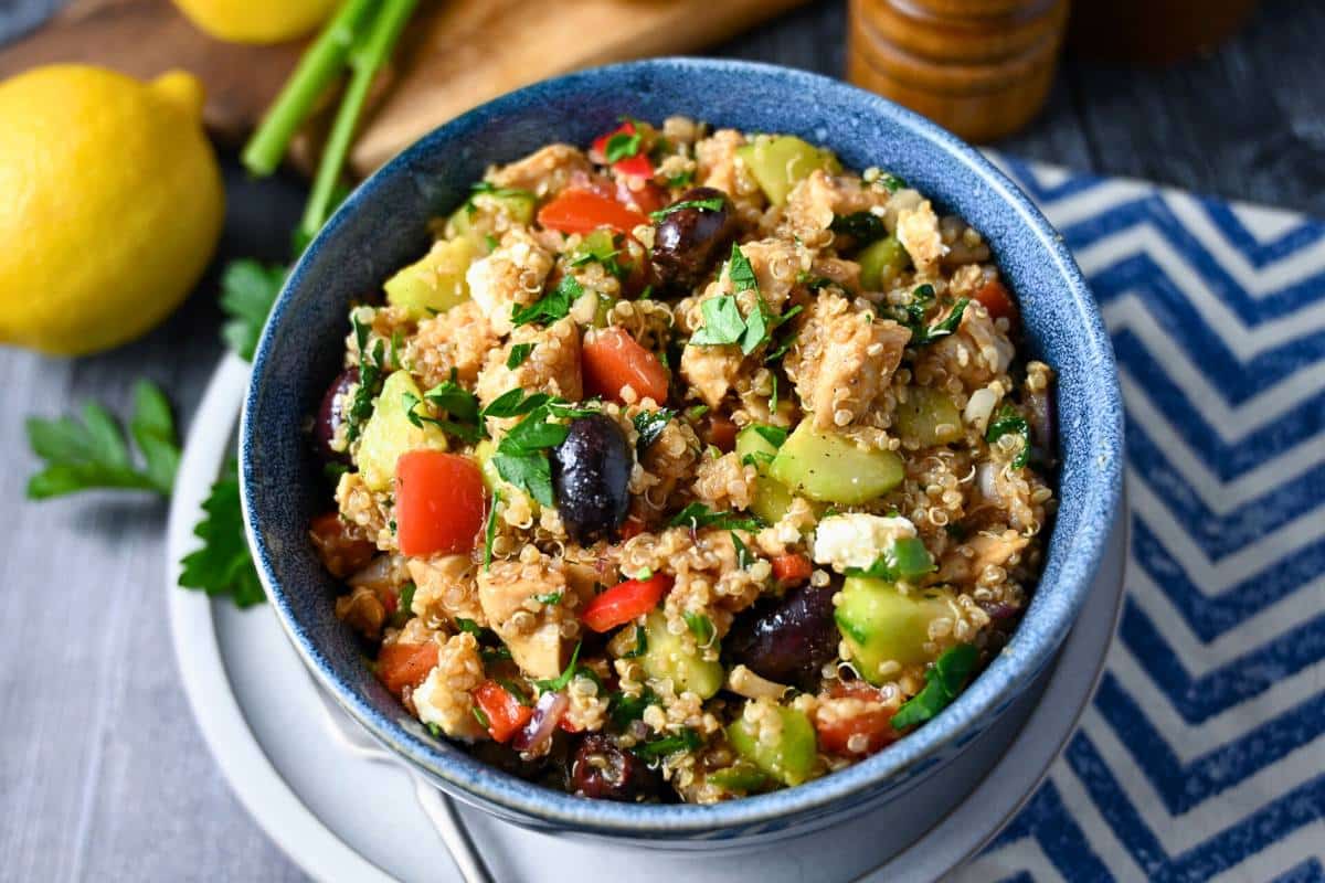 a Mediterranean chicken quinoa bowl with lemons and parsley on the side