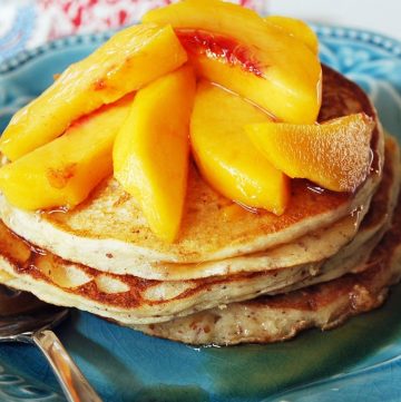 plate of gluten-free protein pancakes with fresh peaches on top