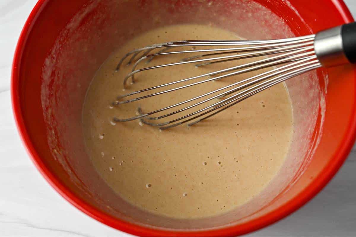 pancake batter with a whisk in a red bowl