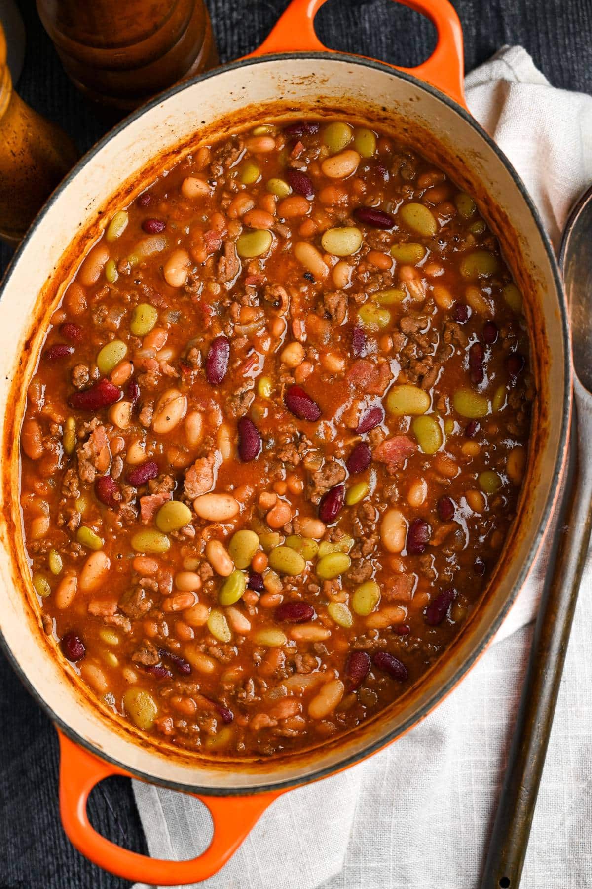 a pot of baked beans with a napkin and spoon