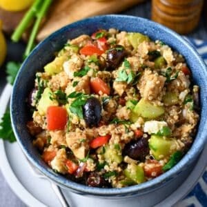 a bowl of greek chicken quinoa salad with a napkin and fork