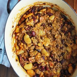 overhead photo of a dutch oven with baked bean casserole in it and a napkin and spoon