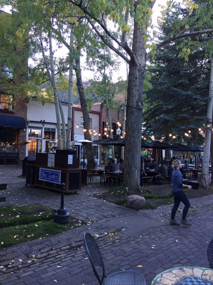 A group of people on a sidewalk next to a tree