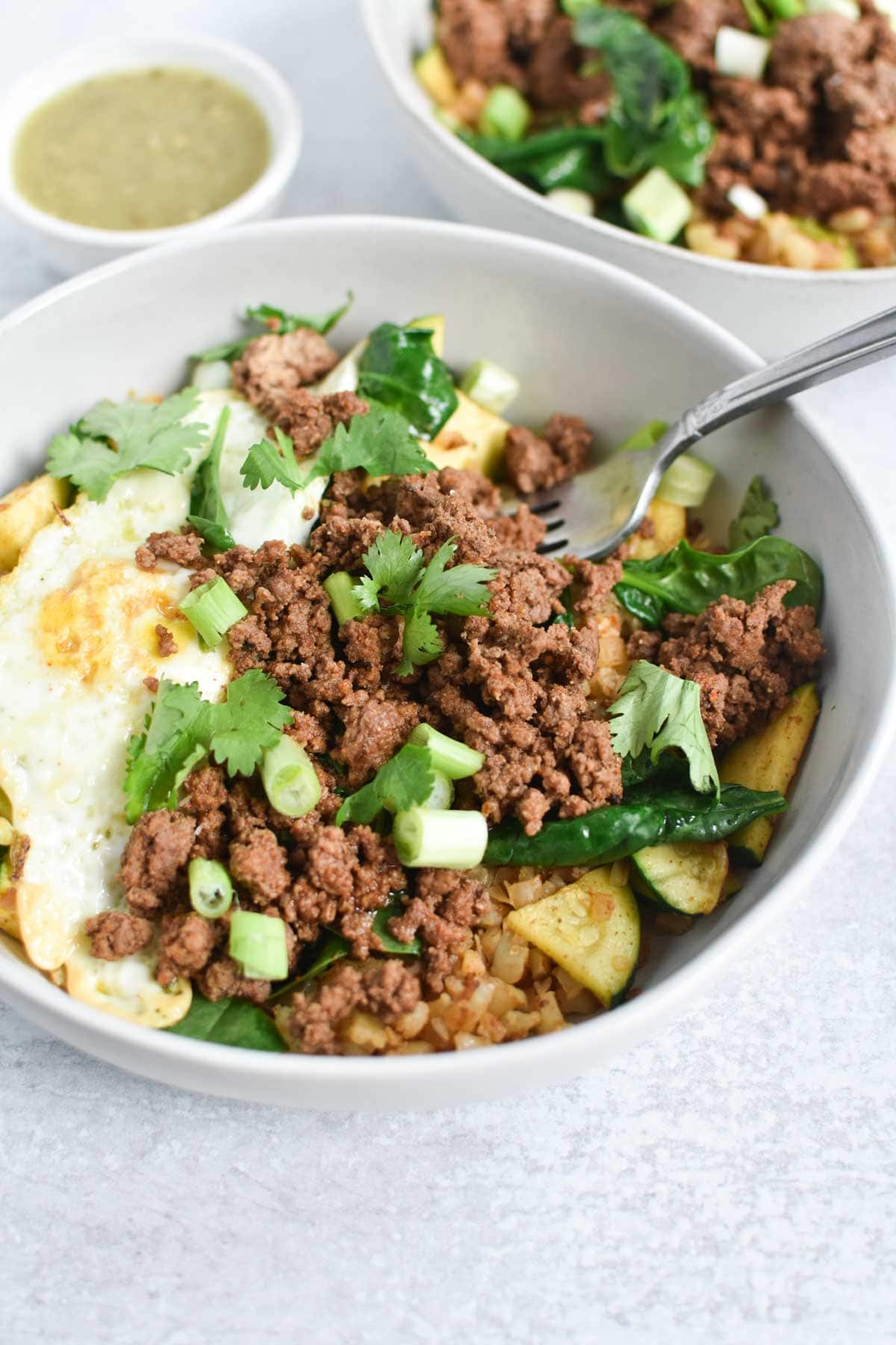 beef with veggies and an egg in a bowl with a fork