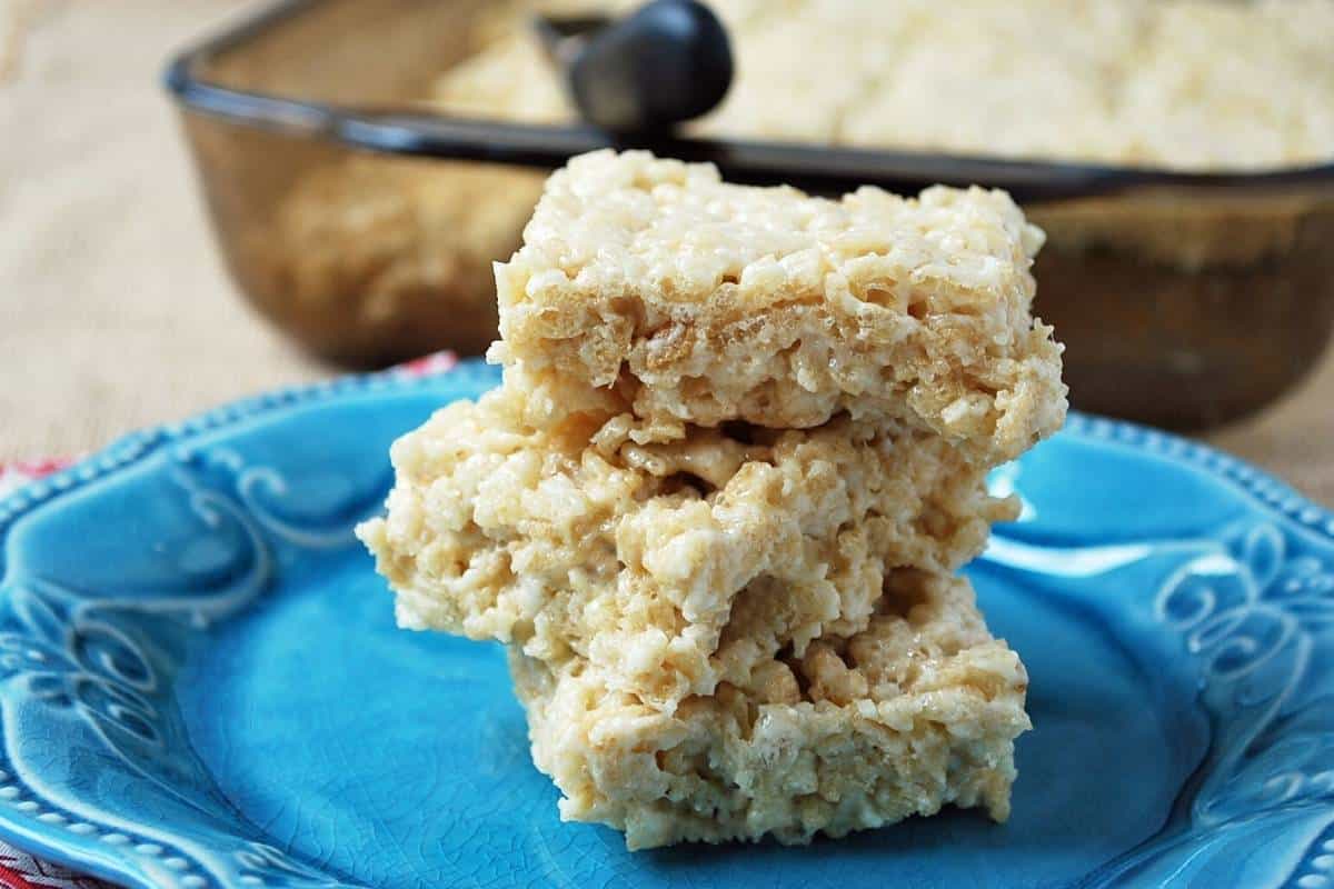 protein rice crispy treats stacked in a pile of 3 bars with pan behind it
