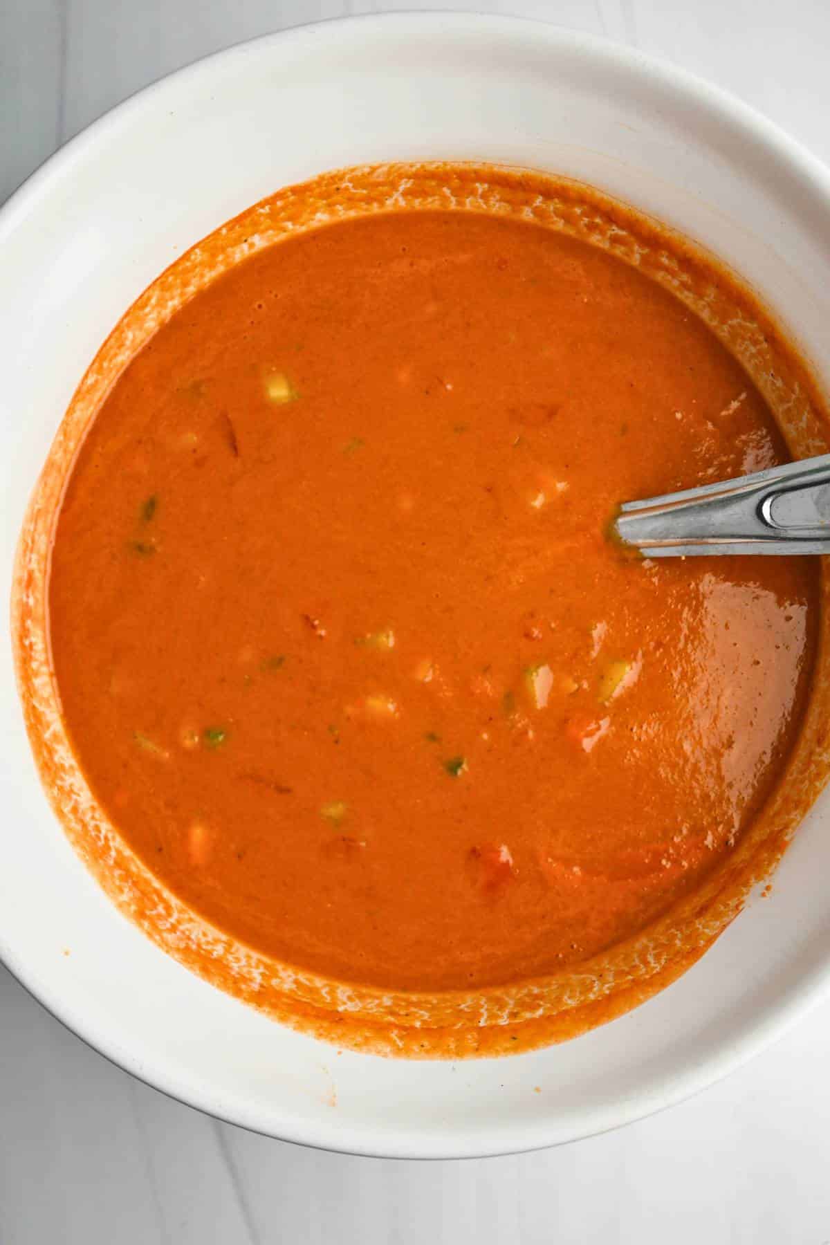 gazpacho soup in a white bowl with a spoon