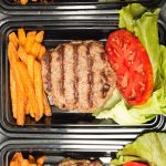 low carb burgers with sweet potato fries, lettuce, and tomatoes in meal prep containers