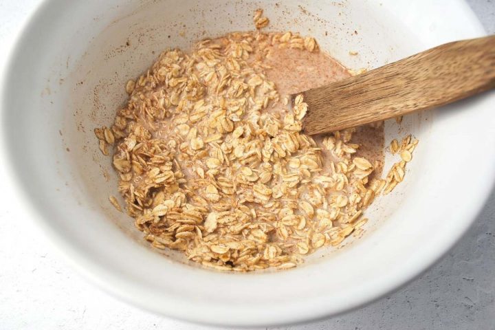 apple pie oat mixture in a large bowl with a wooden spoon