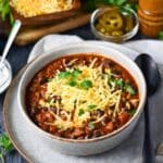 a bowl of beef and black bean chili with cheese and cilantro on top