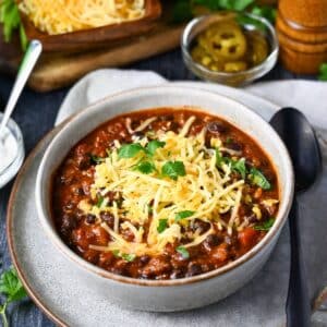 a bowl of beef and black bean chili with cheese and cilantro on top