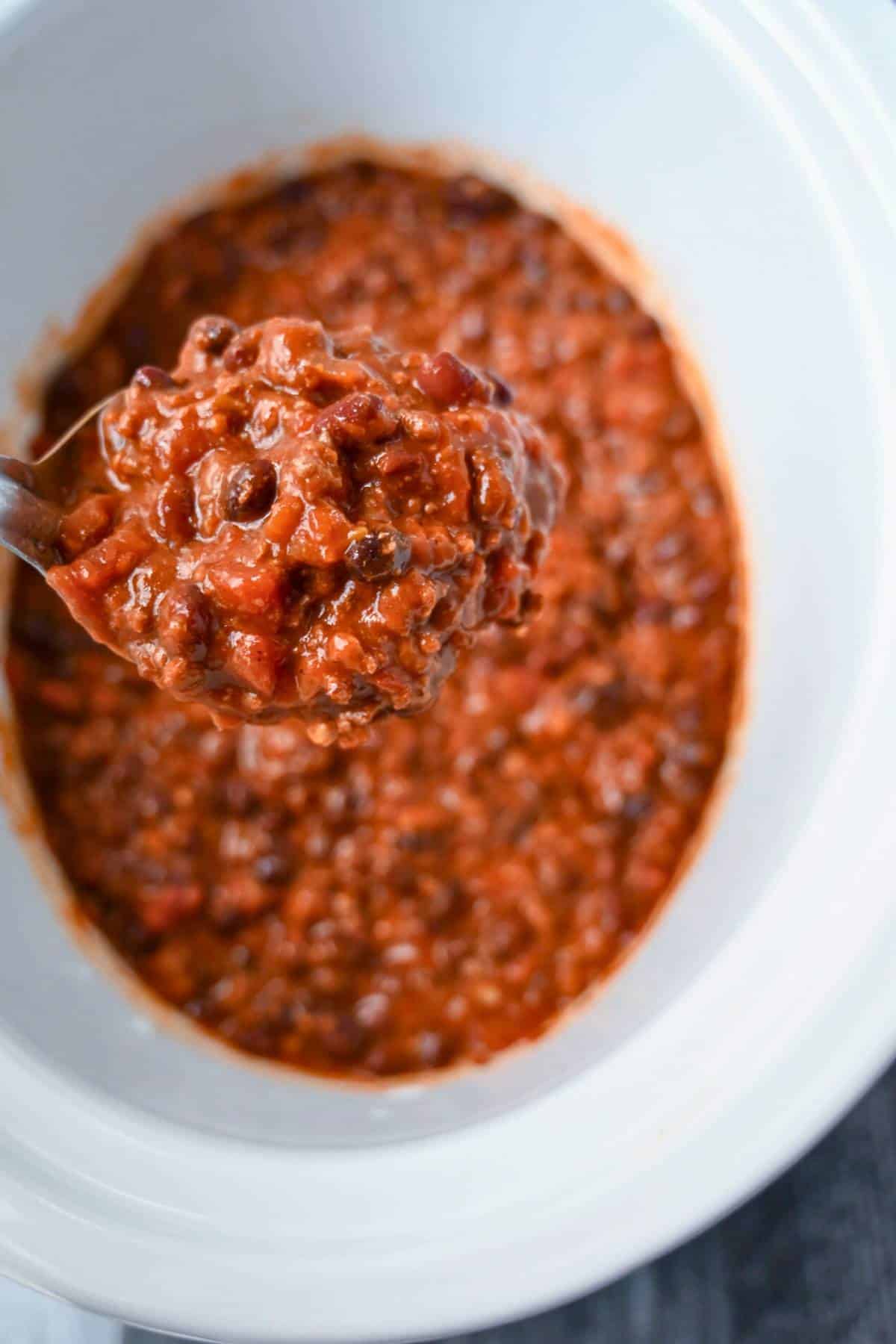 holding up a serving spoon of cooked chili