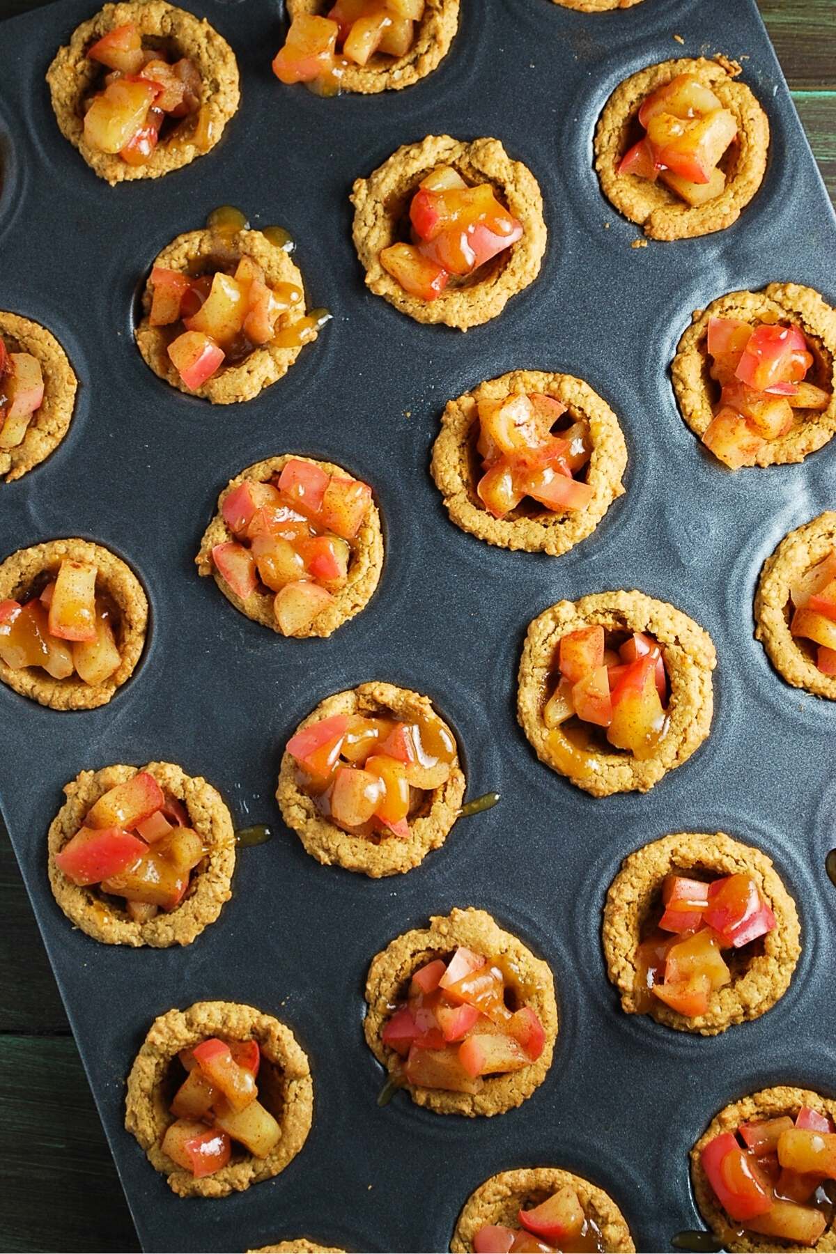 peanut butter apple caramel tarts in a mini muffin pan drizzled with caramel