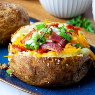 a loaded stuffed baked potato with cheese, meat, bacon, green onions, and sour cream
