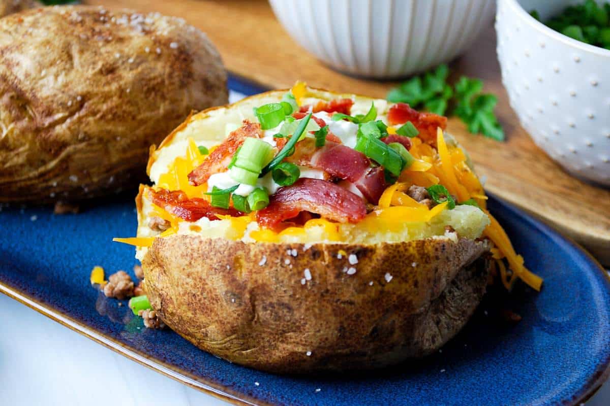 a loaded baked potato with coarse salt around the sides on a blue platter