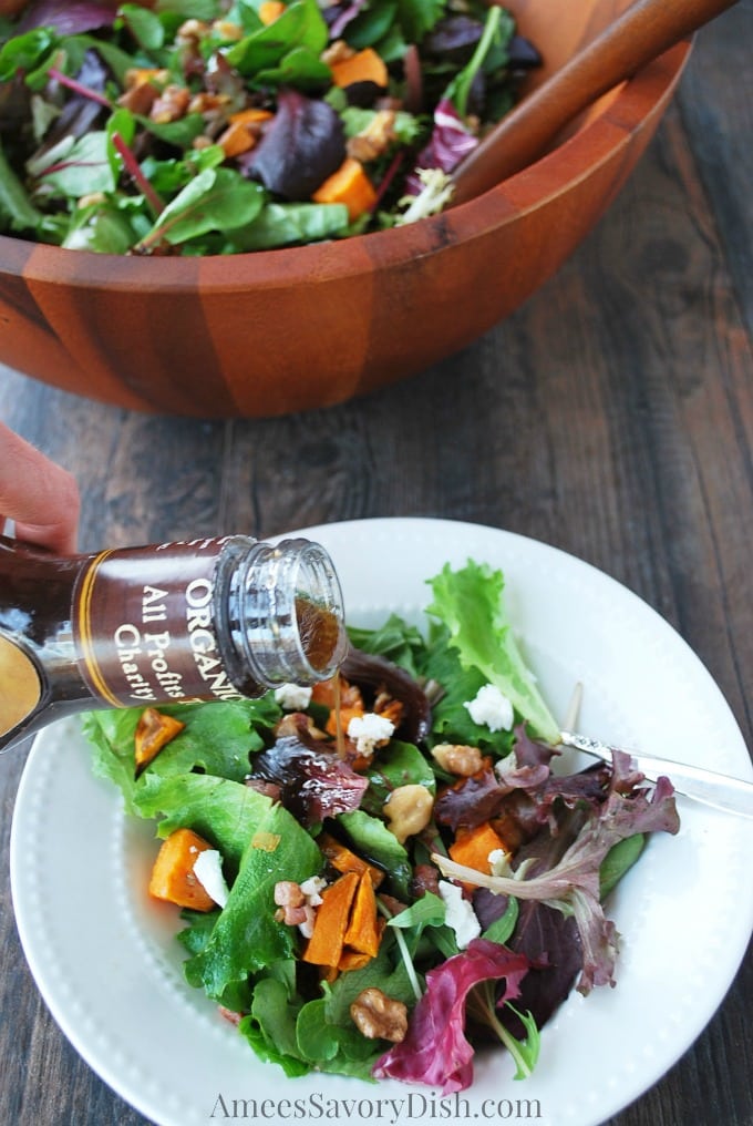 Sweet potato salad in a serving bowl with a bowl of salad in front pouring dressing on top