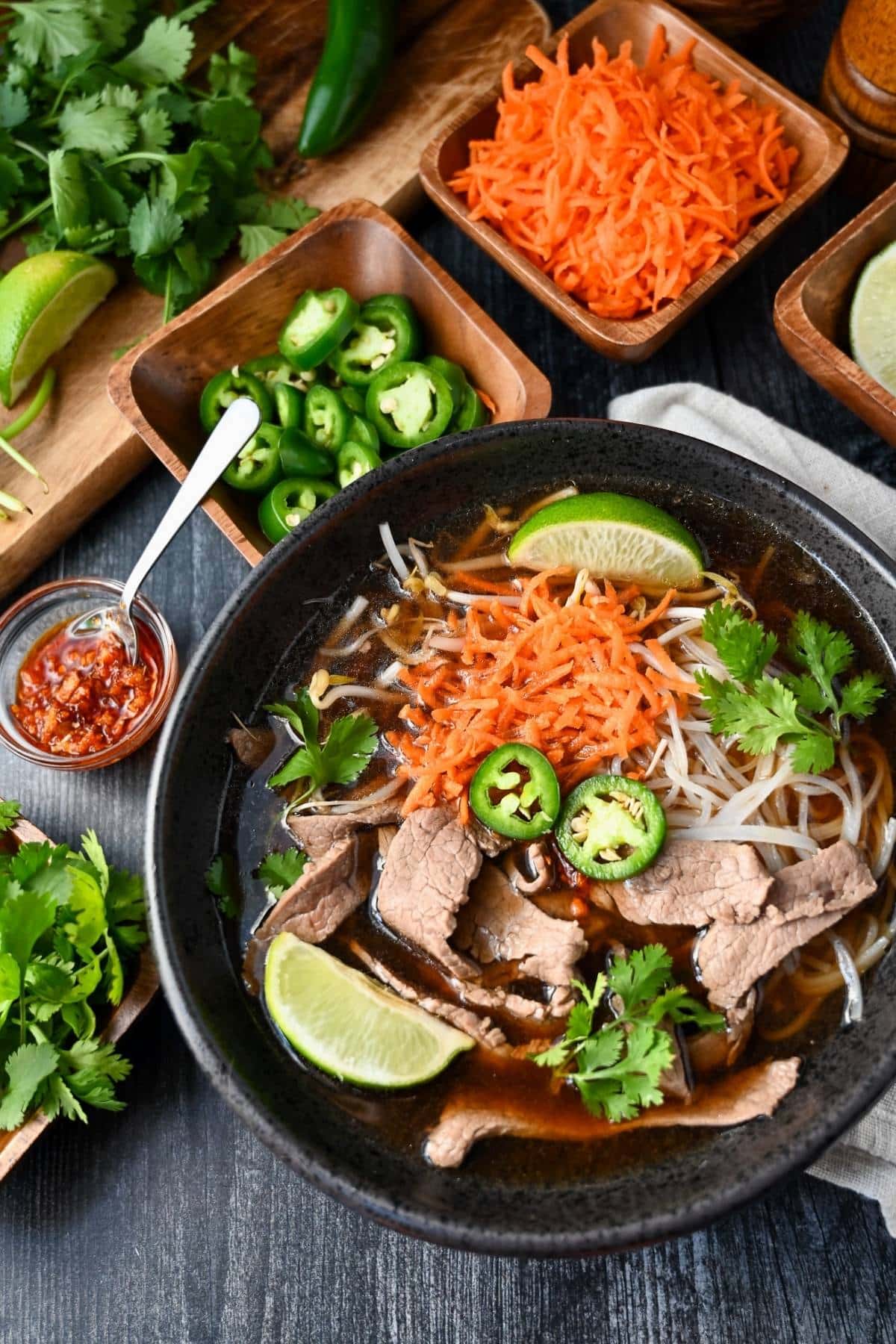 a bowl of beef pho with flank steak and toppings