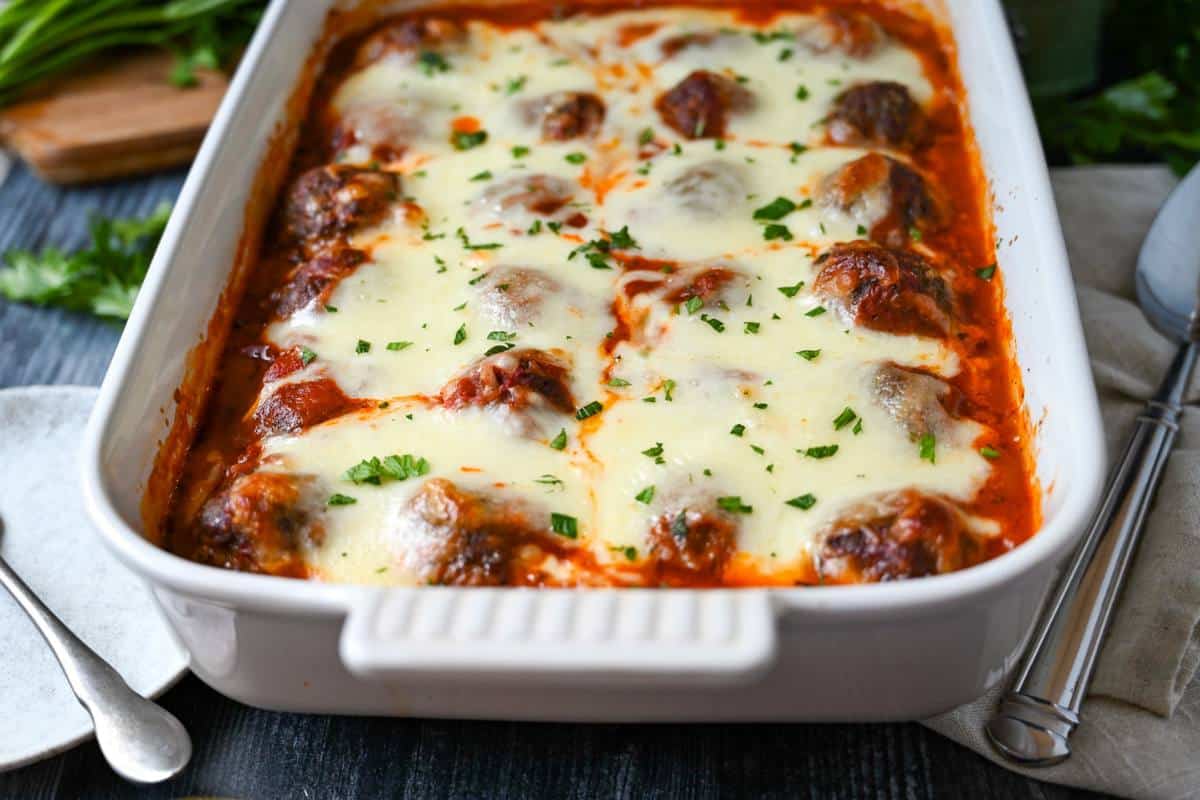 side view of a baked meatball casserole with a serving spoon and napkin