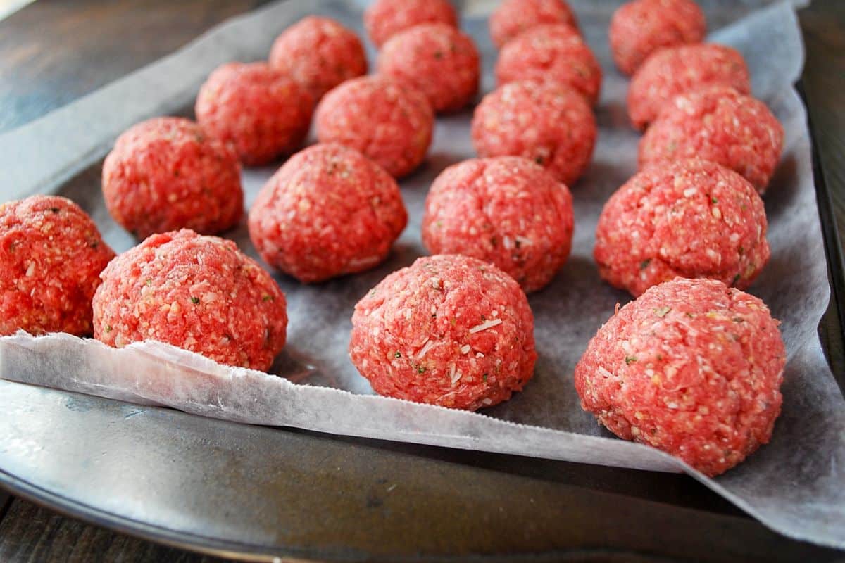 rolled meatballs on a parchment lined baking sheet