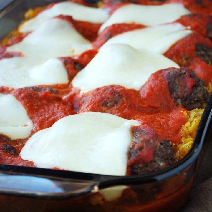 close up photo of spaghetti squash in a baking dish topped with meatballs, marinara sauce, and fresh sliced mozzarella