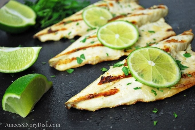 Sea Bass on a cutting board topped with fresh lime and herbs