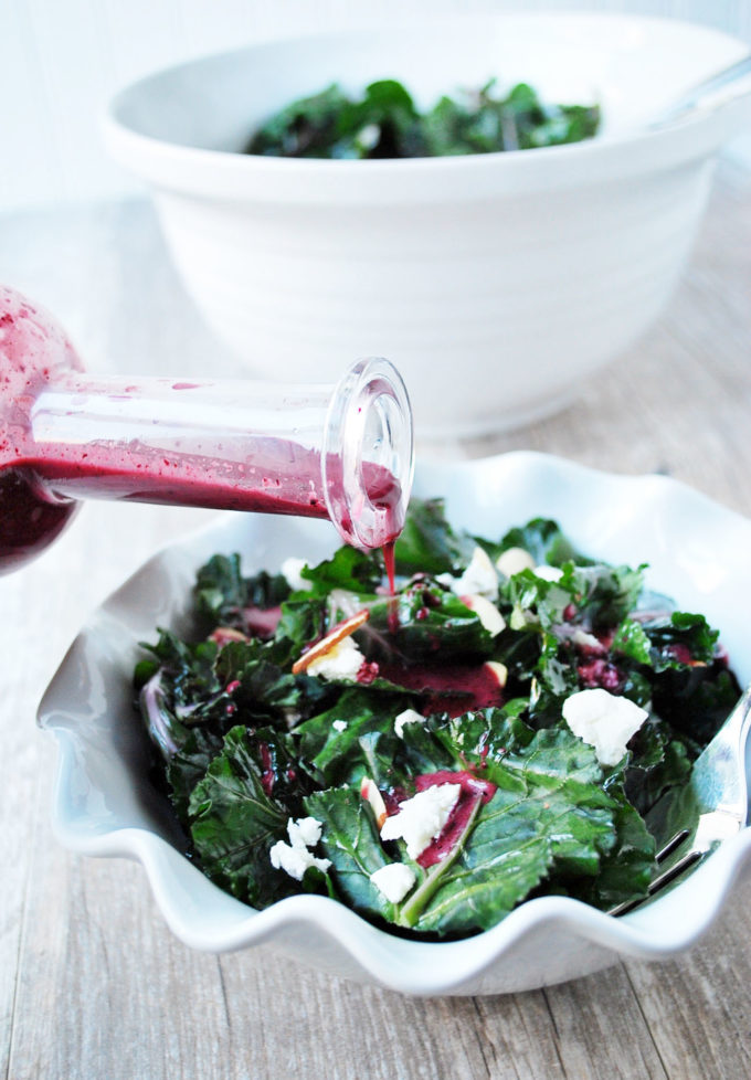 Pouring blueberry vinaigrette on kale superfood salad