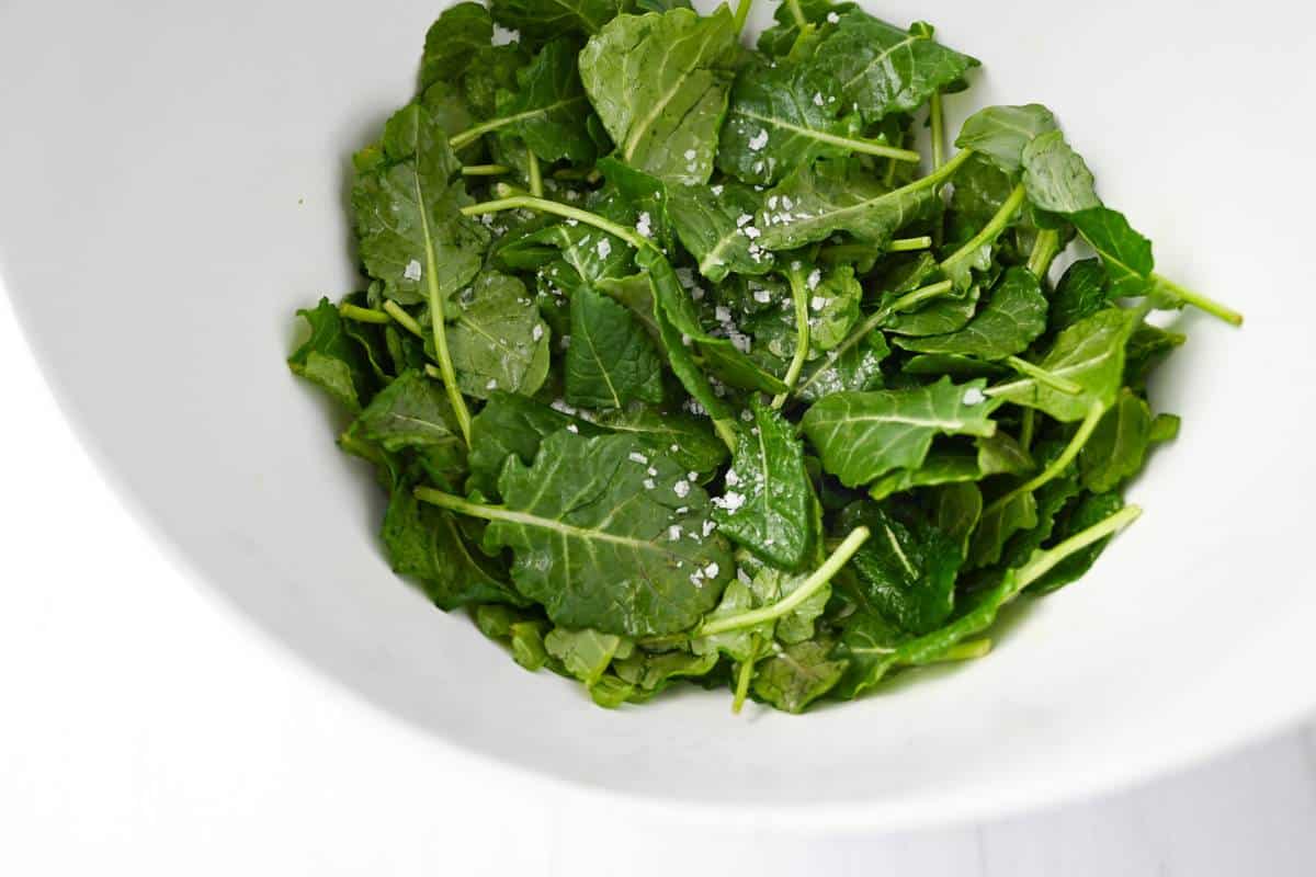 baby kale massaged with olive oil in a bowl with salt
