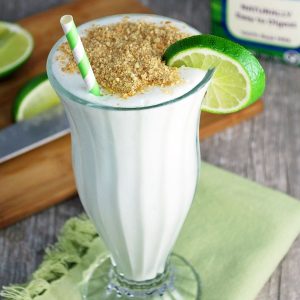 glass of key lime pie smoothie with graham cracker crumbs on top with straw