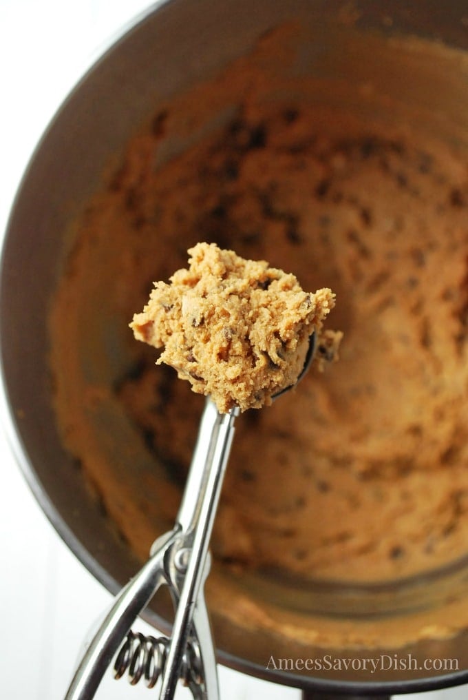 cookie scoop full of cookie dough over a mixing bowl