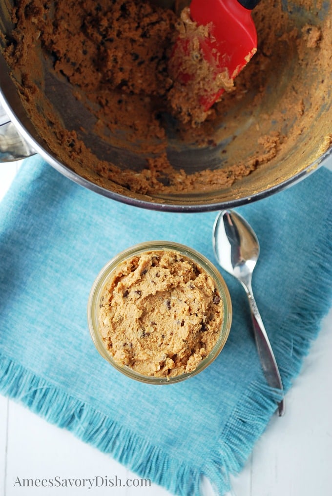 mixing bowl full of cookie dough with a jar of cookie dough in front of it with a spoon