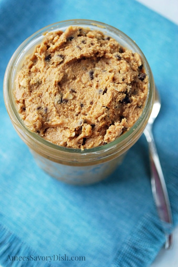 overhead photo of cookie dough in a jar on top of a blue napkin with a spoon