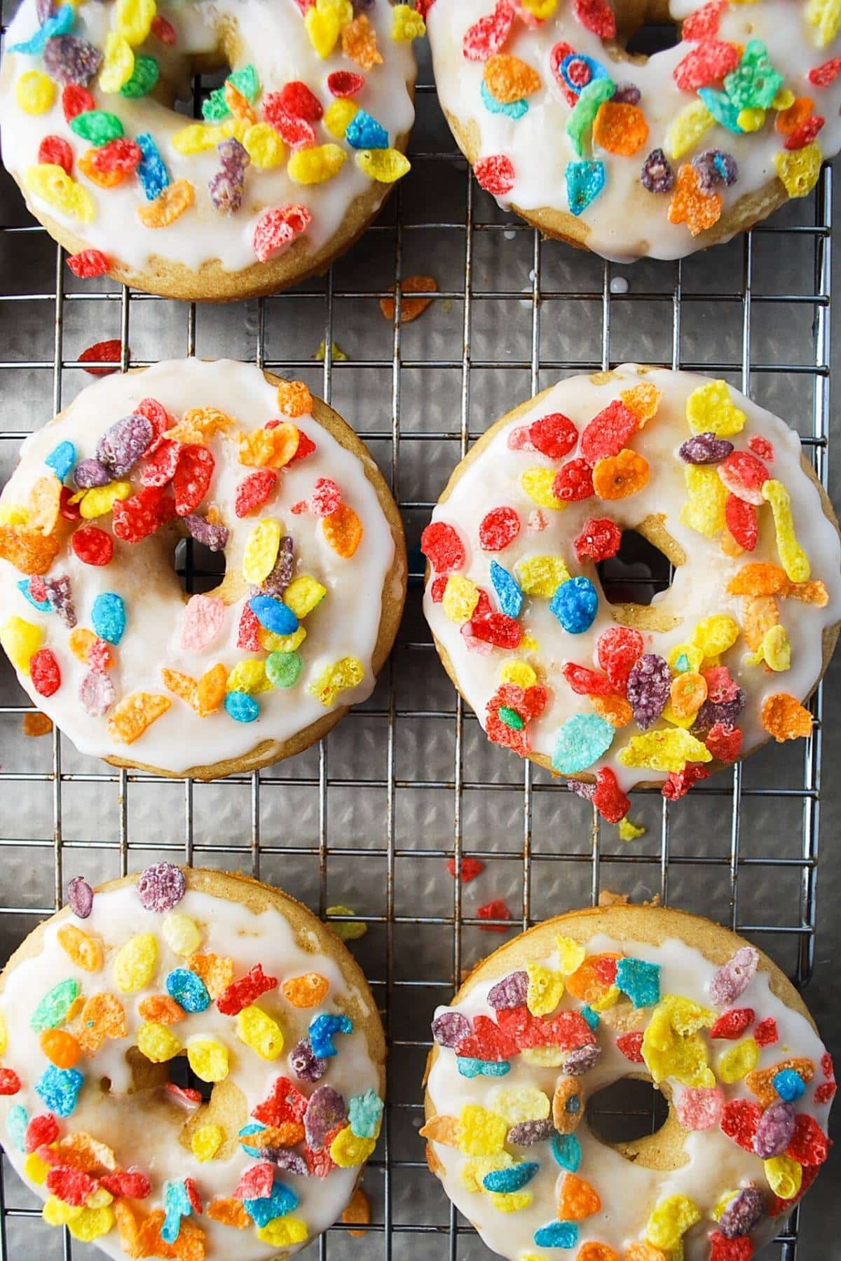 protein donuts on a cooling rack coated in glaze and sprinkled with fruity pebbles
