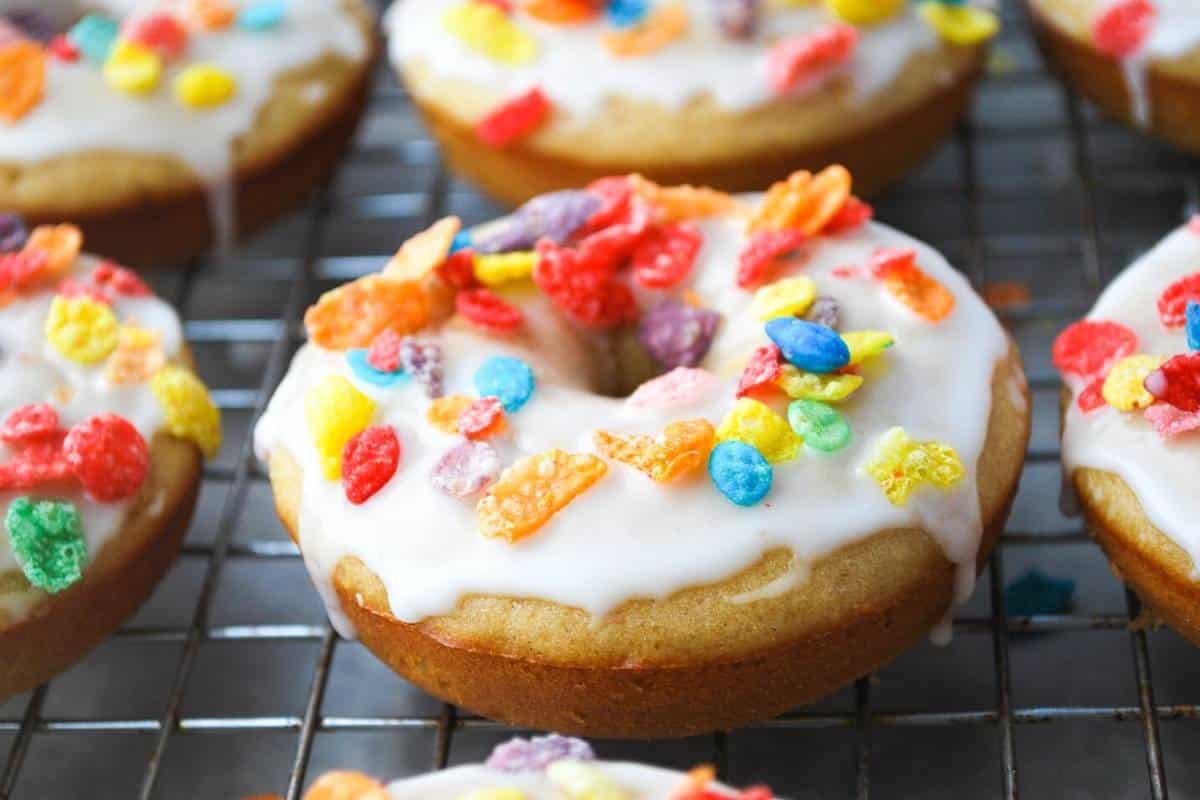 side view of protein donuts glazed and sprinkled with fruity cereal on a rack