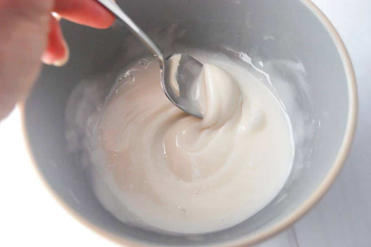 donut glaze stirred in a small gray bowl with a spoon