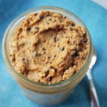 close up of chocolate chip cookie dough in a mason jar with a spoon