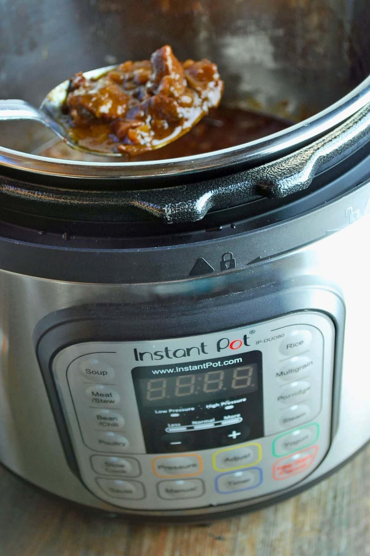 the front of an instant pot with a spoonful of cooked beef stew