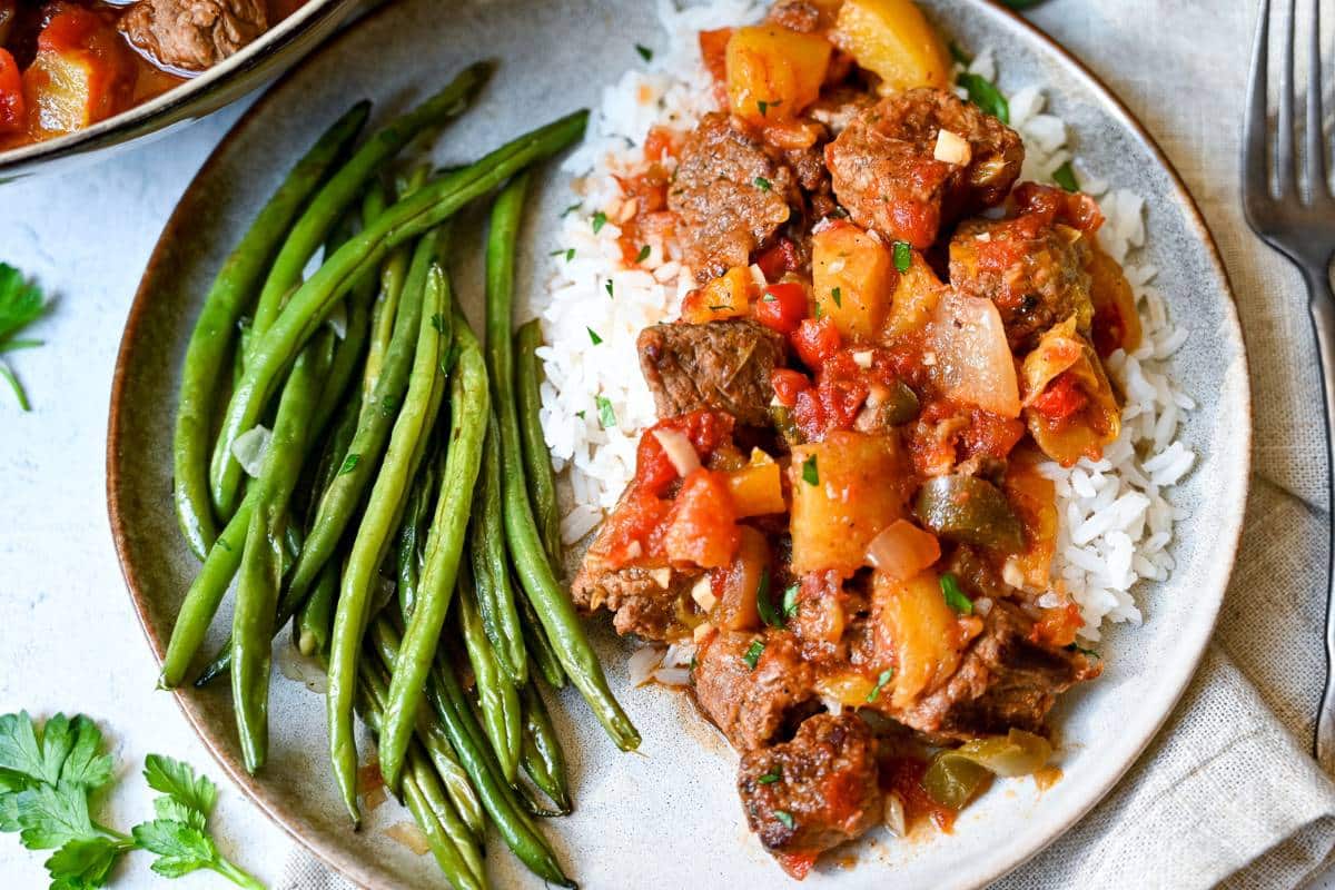 overhead photo of mango beef on a plate with Jasmine rice and green beans with a fork