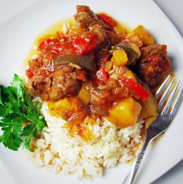 Cubed beef with peppers and mango over rice with a sprig of parsley on the side